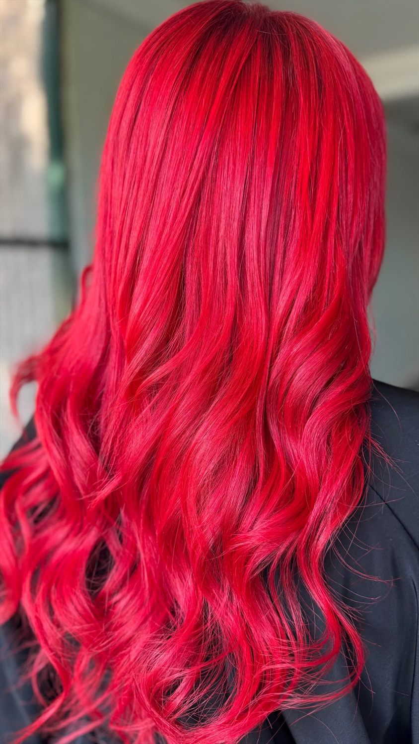 Vivid fire-engine red hair colour with glossy, bouncy waves on long hair, styled at Lucille The Hair Witch